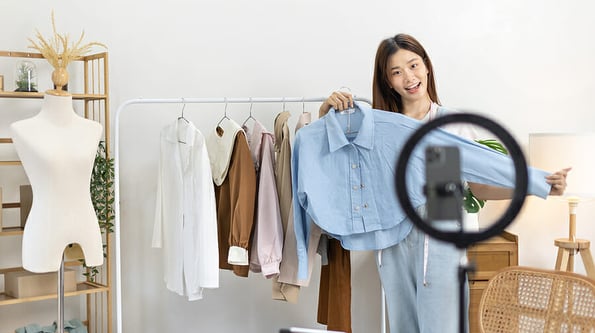Beautiful woman with social media influences performing live or recording shows selling cheap fashion clothes in her studio, Recording vlog video live streaming, Online fashion clothing business.