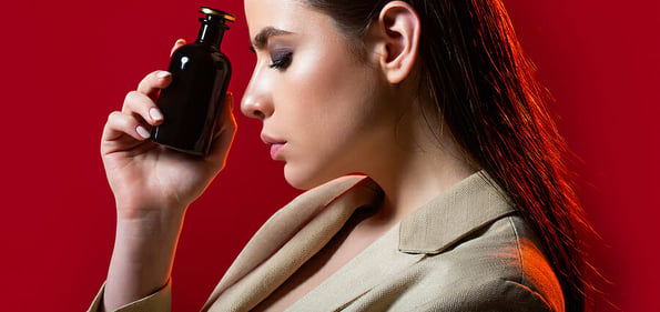 Beautiful girl using perfume. Woman with bottle of perfume. Woman presents perfumes fragrance. Woman perfumes bottle. Red lip
