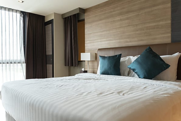 Hotel room with king size bed and floor windows. Design bedroom contemporary style room with wooden furniture white interiors and textiles. the bedroom has a large window bright colors.