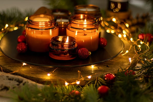 Soy candles burn in glass jars. Comfort at home. Candle in a brown jar. Scent and light. Scented handmade candle. Aroma therapy. Christmas tree and winter mood. Cozy decor. Festive garland decoration