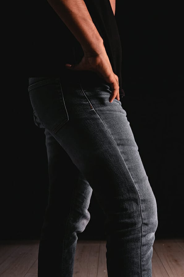 Waist of a man with a black shirt and jeans taking his jeans with his hand. Man dressed in black t-shirt and gray jeans. High quality photo
