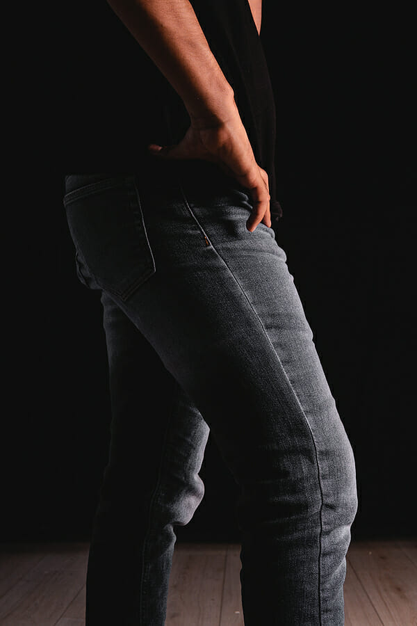 Waist of a man with a black shirt and jeans taking his jeans with his hand. Man dressed in black t-shirt and gray jeans. High quality photo