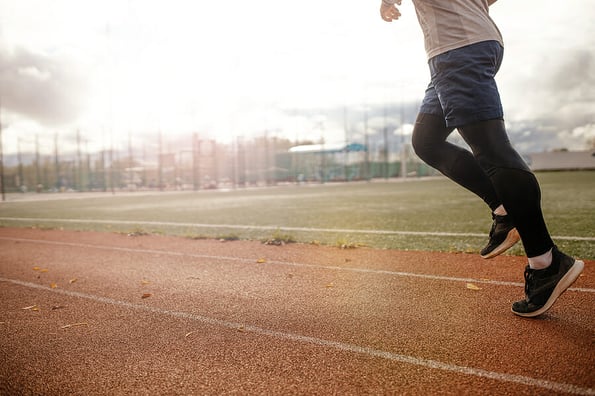 Legs of a runner Running along the stadium tracks close-up . Men's workout sunset jog workout Welness concept.