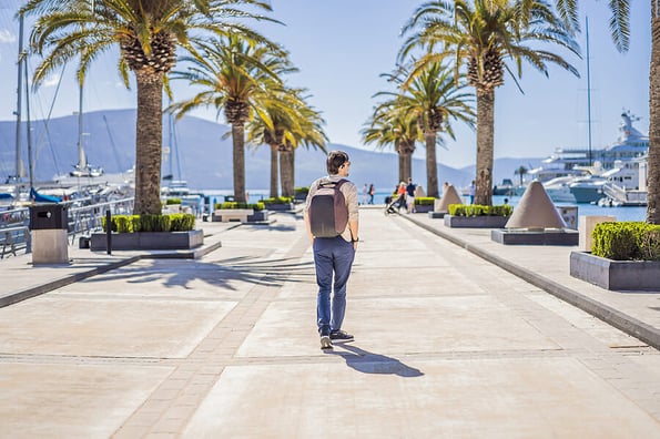 Man tourist on background of Yacht marina, beautiful Mediterranean landscape in warm colors. Montenegro, Kotor Bay, Tivat city. Porto Montenegro marina view. Go Everywhere. Travel around Montenegro concept