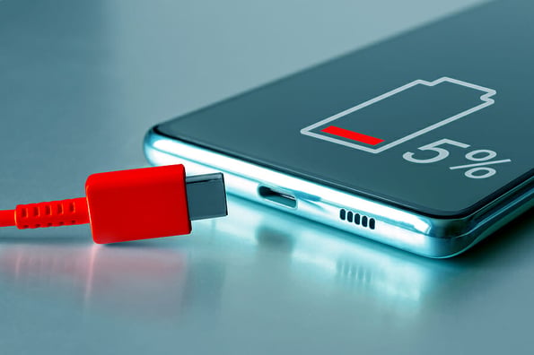 USB Type-C cable and smartphone. Discharged smartphone with low battery icon and red charging Type C cable. Dangerously low charge, fast battery wear and tear, urgent quick charge.