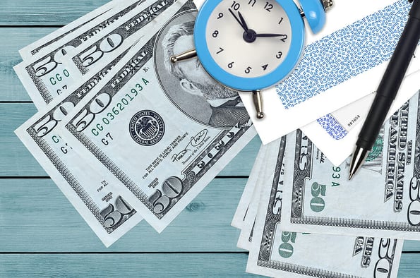 50 US dollars bills and alarm clock with pen and envelopes. Tax season concept, payment deadline for credit or loan. Financial operations using postal service