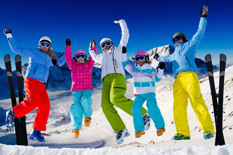 Family skiing and jumping together on a sunny mountain slope during winter vacation.