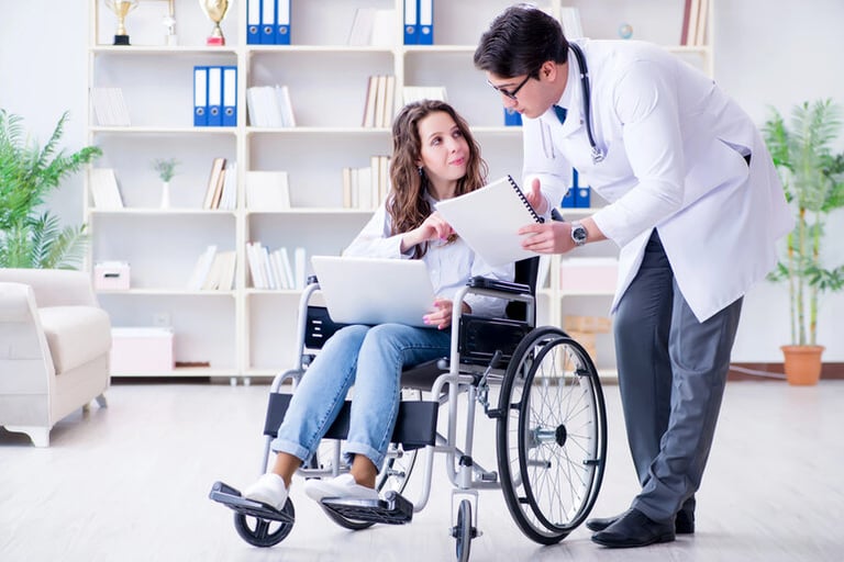 Doctor reviewing documents with a wheelchair user during a medical consultation after an unexpected injury.