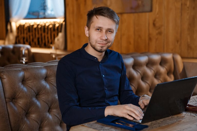 Uri Poliavich, as a representative of the new digital generation, is shown sitting on a sofa using a laptop, symbolizing modern entrepreneurship and digital-driven business leadership.