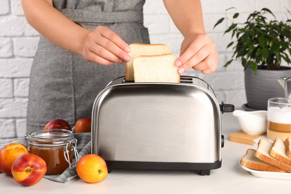 closeup of a woman putting bread into toaster in kitchen