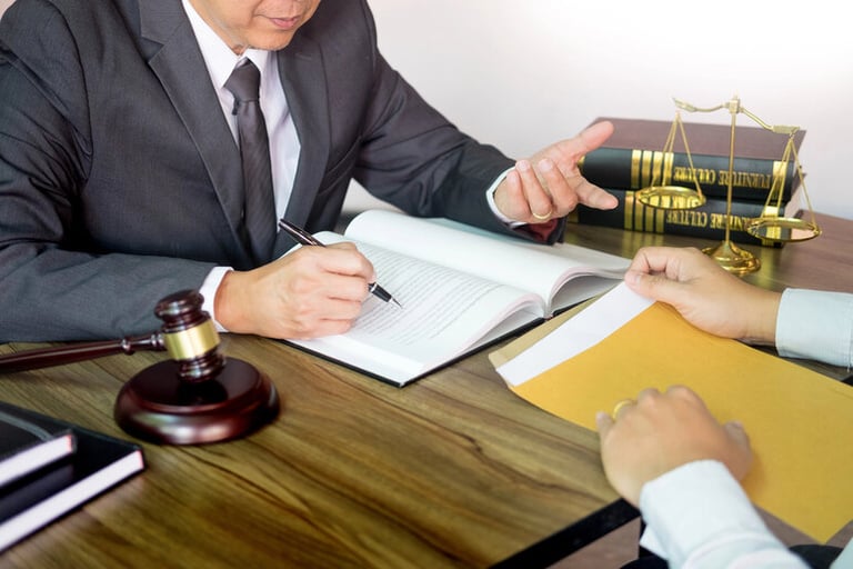 Attorney consulting with a client over legal documents in an office, symbolizing legal guidance and support for whistleblowers reporting workplace misconduct.