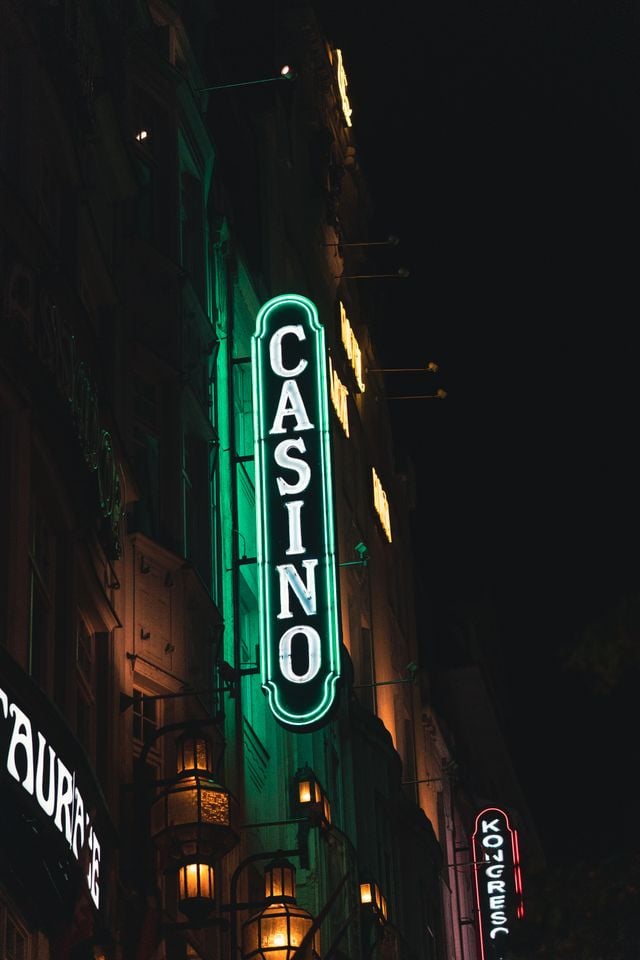 Vertical shot of a bright green neon casino sign illuminating the night street.