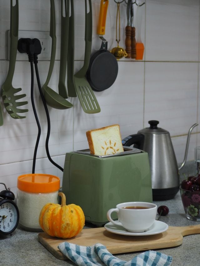 Toaster with sun printed on it in a warm kitchen setting with tea, ideal for cozy morning vibes.