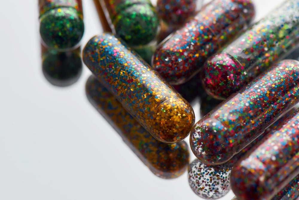 colorful glitter pills scattered, lying randomly on light background. Minimal style, art concept