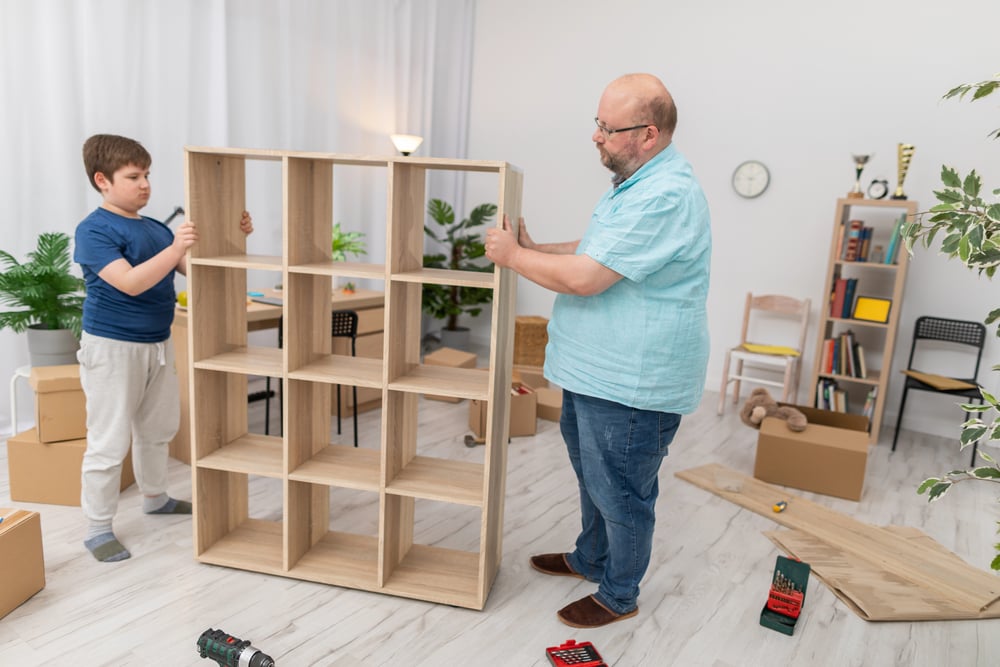 Father and son moving a folded bookcase into place