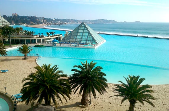 View of San Alfonso del Mar, featuring its iconic heated swimming pool, known as “la piscina temperada” or simply “the pyramid,” with the Pacific Ocean in the background.