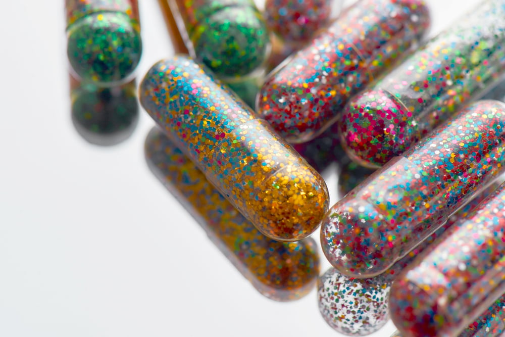 colorful glitter pills scattered, lying randomly on light background. Minimal style, art concept