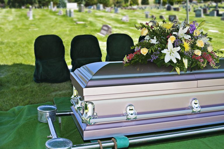 Image of a steel Casket with Flowers on top in a cemetery