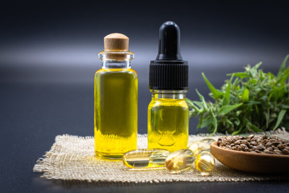 Glass bottle with CBD hemp oil and medicine extracted from hemp oil, placed on a black background hemp bag CBD hemp oil concept. Alternative medicine Herbs extracted from nature, close-up image
