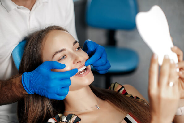 Dental clinic. Reception, examination of the patient. Teeth care. Young woman undergoes a dental examination by a dentist.Happy patient and dentist concept.Male dentist in dental office talking with girl patient.Beautiful teeth dentist