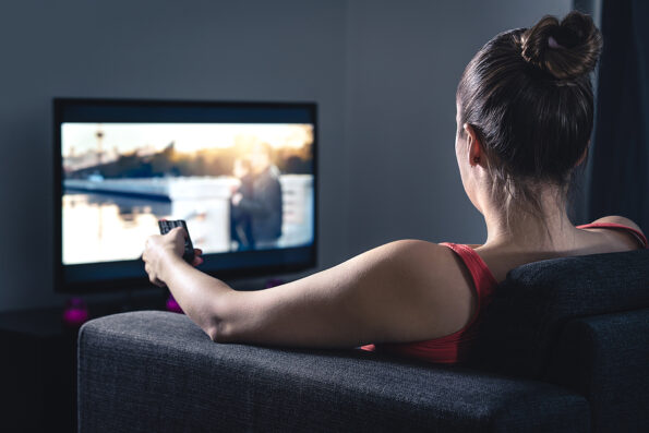Woman streaming movie or watching series. Person using smart tv remote control to choose film or change channel. Stream or video on demand (VOD) service in television screen. Digital entertainment. shows