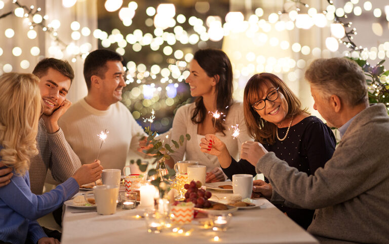 celebration, holidays and christmas concept - happy family with sparklers having fun at dinner party at home