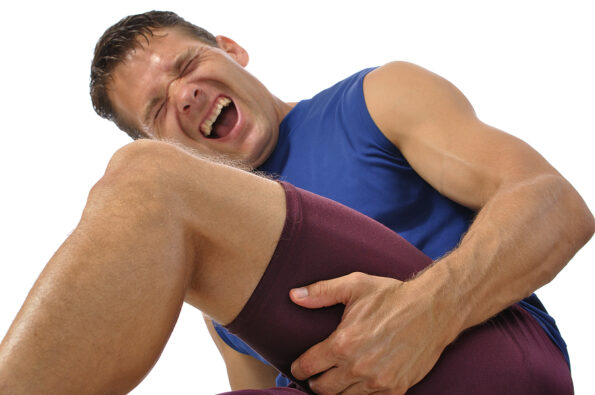 Male athlete clutching his hamstring in excruciating pain on white background