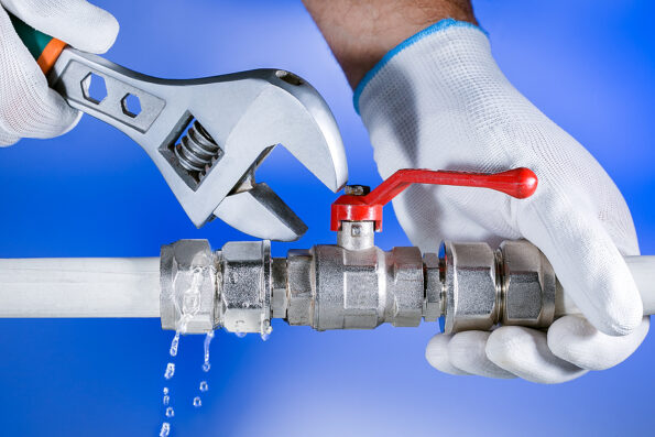 Hands plumber at work in a bathroom, plumbing repair service. Leak of water. Repair plumbing.