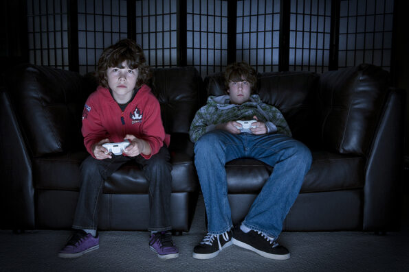 Two boys sitting on a couch playing video games