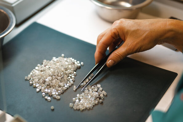 Manual sorting of diamonds. A hand with tweezers transfers diamonds from one pile to another.