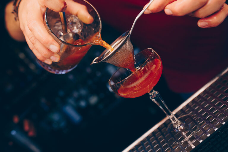 Bartender pouring using strainer White healthy Cocktail drink on a bar counter . Professional view . Trendy stylish alcoholic drink . Design people and luxury concept service barman in nightclub