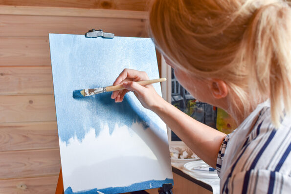 Girl artist paints a picture on canvas at home with oil paints at home. Lessons at Painting Studio. hobby painting with oil paints. Art therapy painting with brush