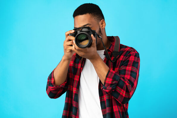 Photography Concept. African American Photographer Man Taking Photo Standing On Blue Background In Studio