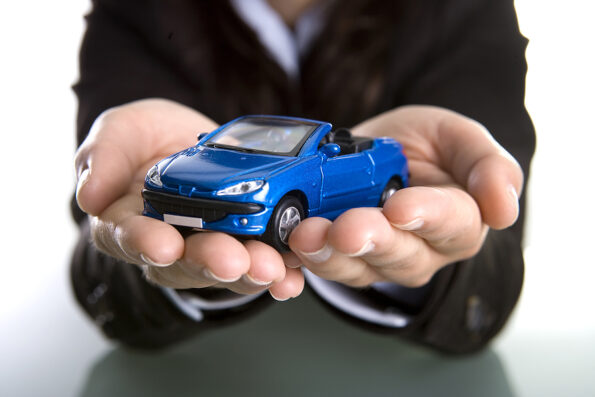 businesswoman holding car in the hands - insurance business concept