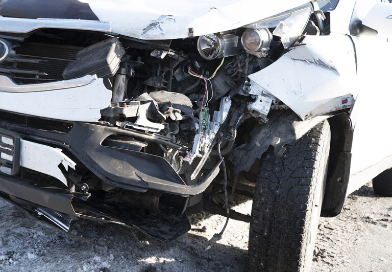 A white car crashed accident. Car accident on the road. Car crash accident on street. Damaged vehicle. Car insurance concept. White color vehicle get big damage by accident on the road.