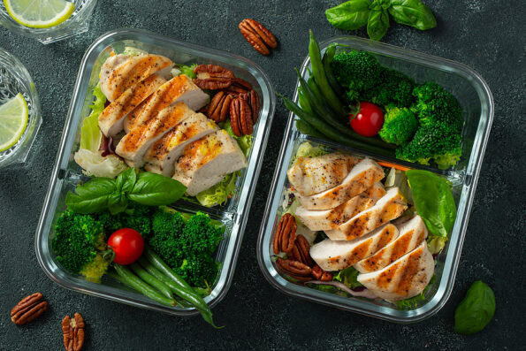 Healthy meal prep containers with green beans, chicken breast and broccoli. A set of food for keto diet in lunchbox on a dark concrete background. Top view