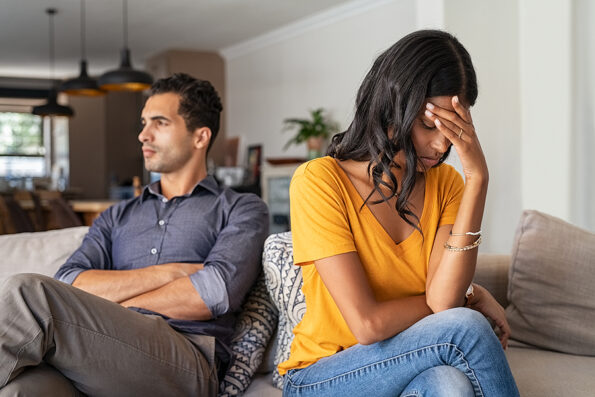 how to stop fighting in a relationship Middle eastern young couple sitting on couch after a fight. Sad indian woman sitting with hand on head after quarrel with boyfriend at home. Angry couple ignoring each other, relationship troubles.