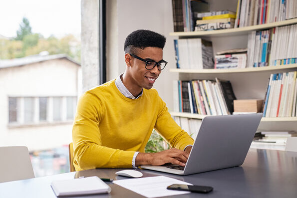 video email African american businessman using laptop at modern office. Happy creative young man feeling successful after receiving approval mail and working from home. Smiling student studying on computer.