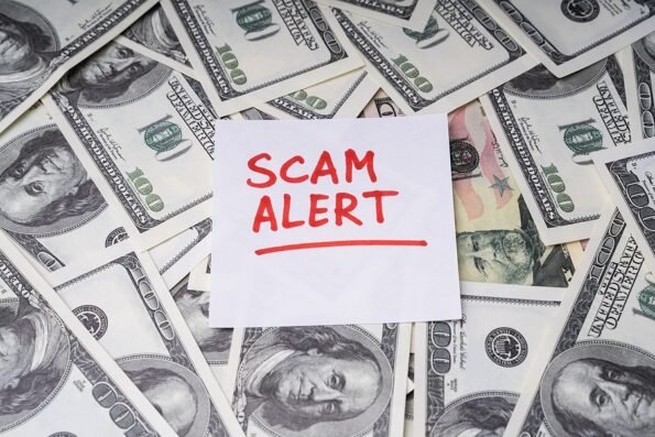 Background Of Dollar Bills With Scam Alert Text Written With Marker On Notepaper