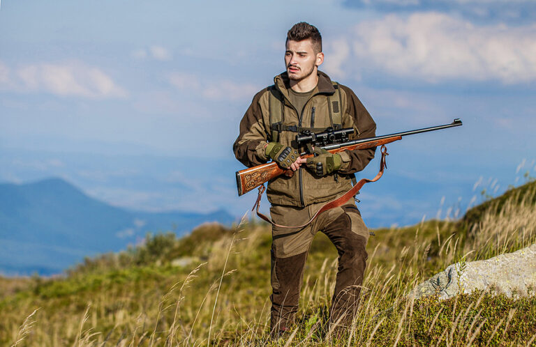 Hunter with hunting gun and hunting form to hunt. Hunter is aiming. Shooter sighting in the target. The man is on the hunt. Hunt hunting rifle. Hunter man. Hunting period. Male with a gun