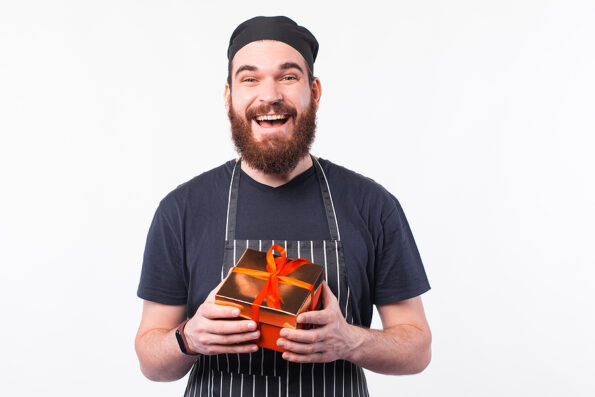 Photo of happy cheerful chef man holding a gift box
