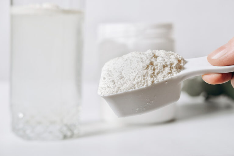 hand holding scoop of fish collagen. collagen peptides in container or jar. powder for mixing drink. Healthcare supplement concept. collagen for skin and joints