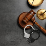 Judge's gavel, handcuffs and scales on grey background, flat lay with space for text. Criminal law concept