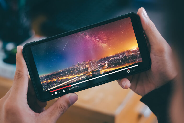 Online movie stream with smartphone. Young man watching film on mobile phone with imaginary video player service.