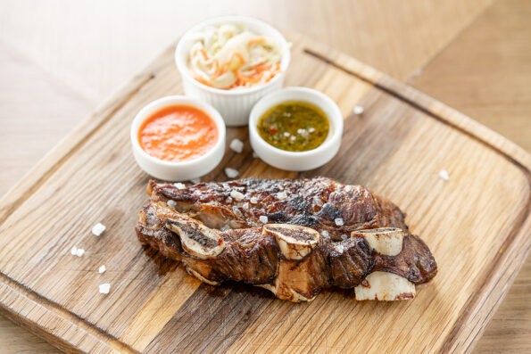Beef meat cut according to the Argentine style, called asado. with Pickled cabbage and two sauces. Serving on a wooden Board. Barbecue restaurant menu, a series of photos of different meats.