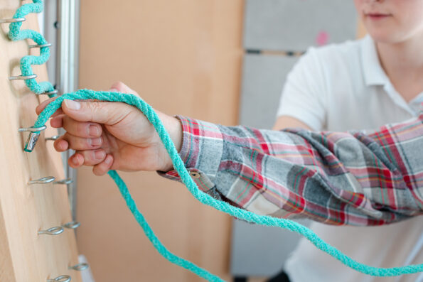 Man in occupational therapy with therapist training his dexterity at the rope board