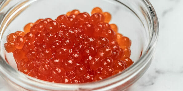 Salmon Red Caviar. Red fish caviar on a spoon in glass bowl. Raw seafood. Luxury delicacy food. appetizer, selective focus, place for text.
