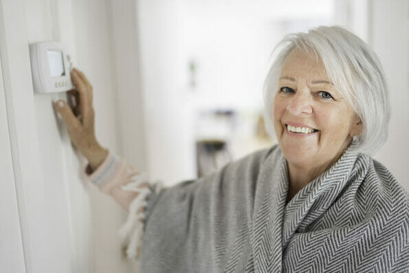Senior woman adjusting her thermostat at home