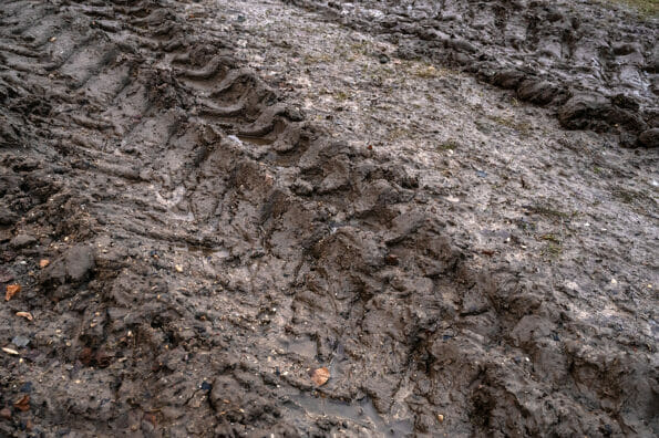 Close-up of tire tracks on muddy rural dirt road in late autumn. Off-road, wild dirt trail showing difficulties of moving people in rural areas during rainy season