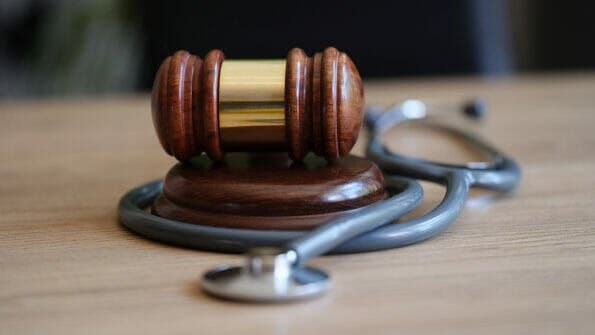 Close-up of judge gavel and doctor stethoscope on lawyer office desk. Medical malpractice, personal injury lawyer and healthcare legal aspects concept